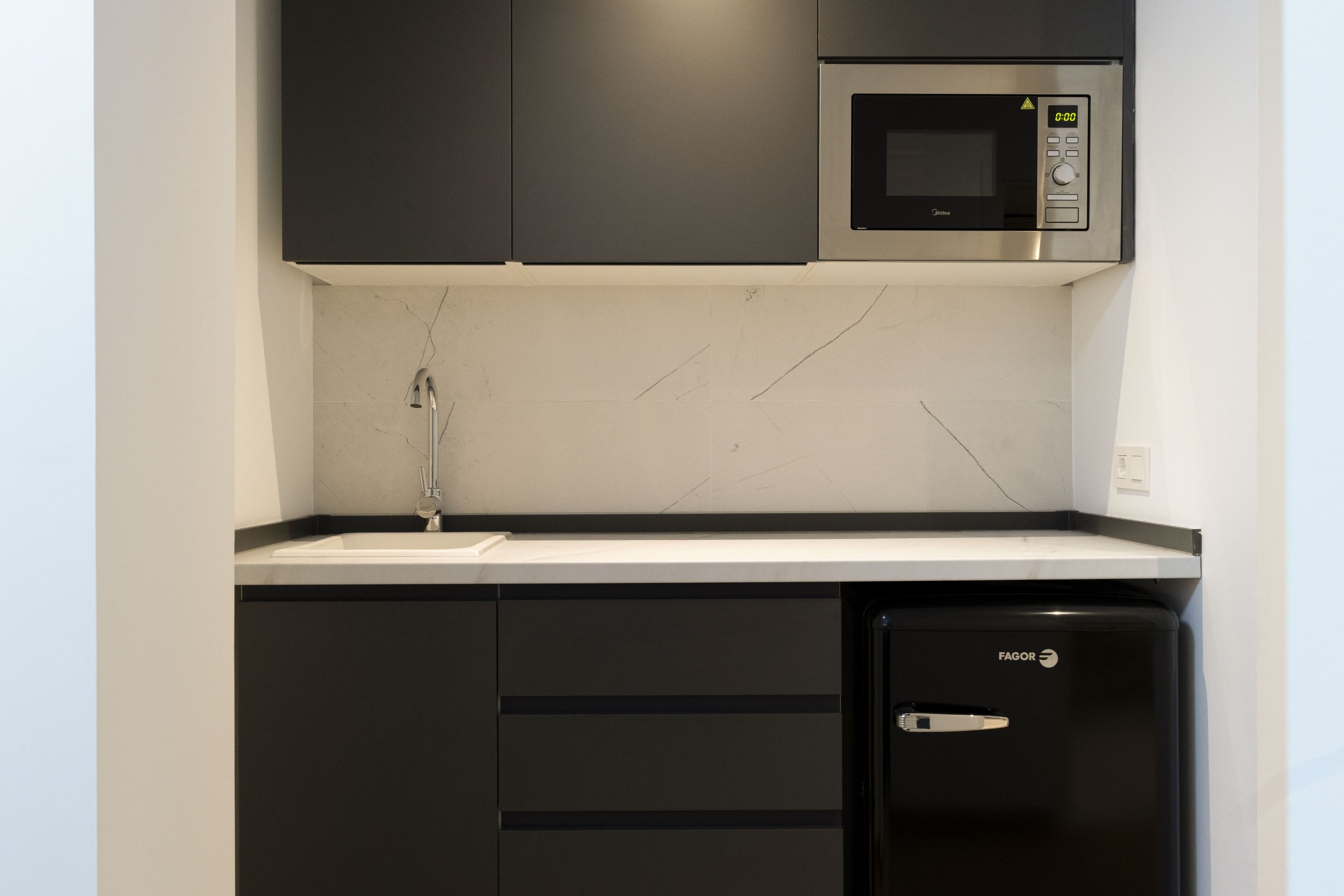 A compact kitchen with a black dishwasher, a microwave, and a sink.