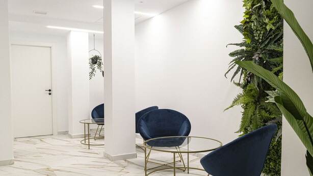 A modern interior with marble flooring, blue velvet chairs, and a green vertical garden. - Forata Lofts, Room 3 (Valencia)