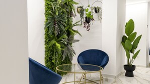 A modern room with two blue chairs, a gold-framed table, and a vertical garden wall. - Forata Lofts, Room 3 (Valencia)