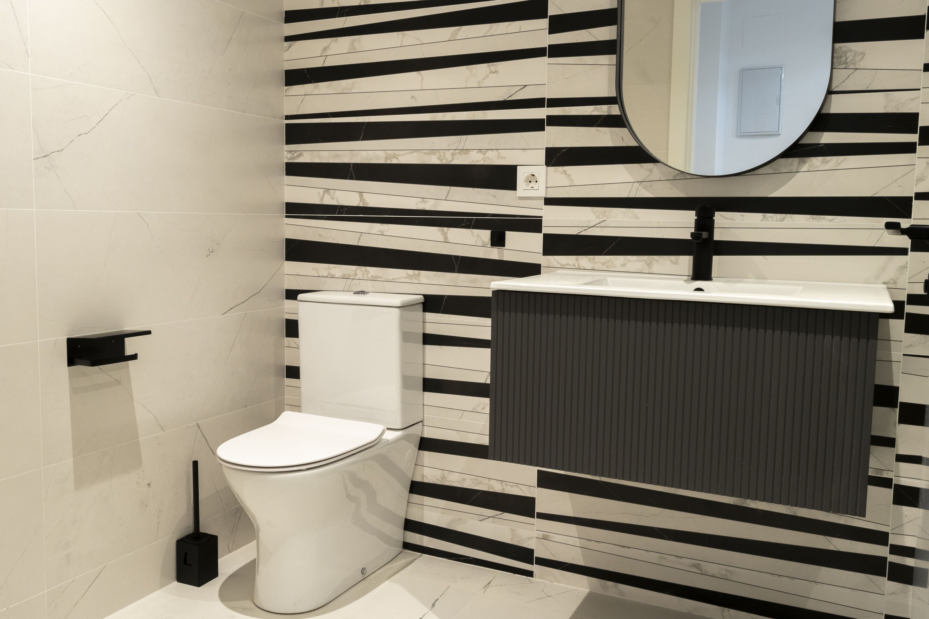 Un baño moderno con inodoro, lavamanos y espejo.