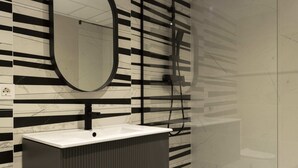 A bathroom with a white sink, black and white striped wall, and a round mirror. - Forata Lofts, Room 3 (Valencia)