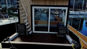 A modern boat with a glass-enclosed upper deck and a wooden lower deck. - Floating apartment in the nautical Vigo ferry dock Cies Islands and Cangas (Vigo)