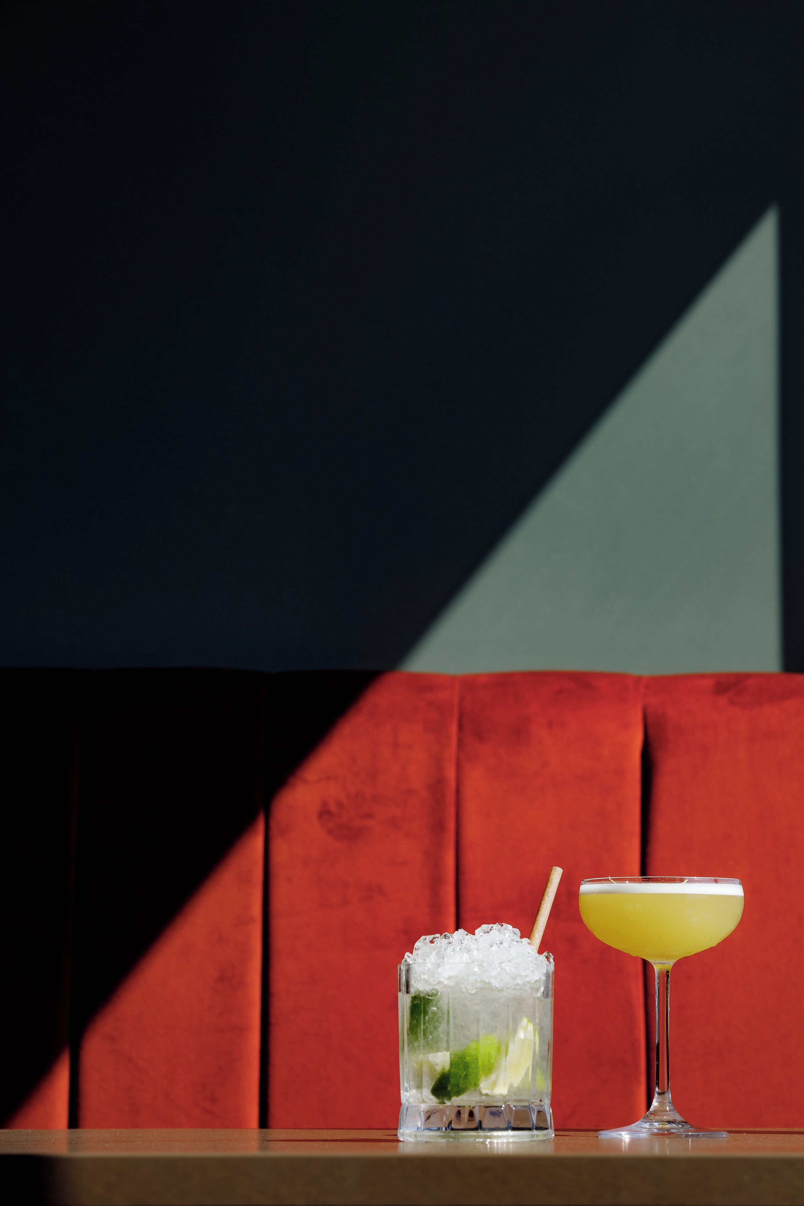Dos bebidas sobre una mesa, con una pared de fondo con diseño geométrico.
