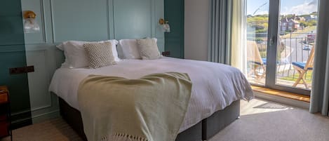 A bedroom with a large bed, a view of the outside, and a balcony with chairs.
