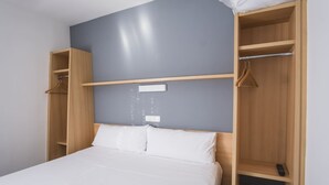 Ein Schlafzimmer mit einem Bett, einem Kleiderschrank und einem Regal mit einer Fernbedienung.