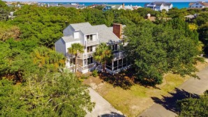A coastal house with a balcony, surrounded by dense greenery and a clear view of the ocean. - Hellenic Haven 6 Bedroom Home (Georgetown)