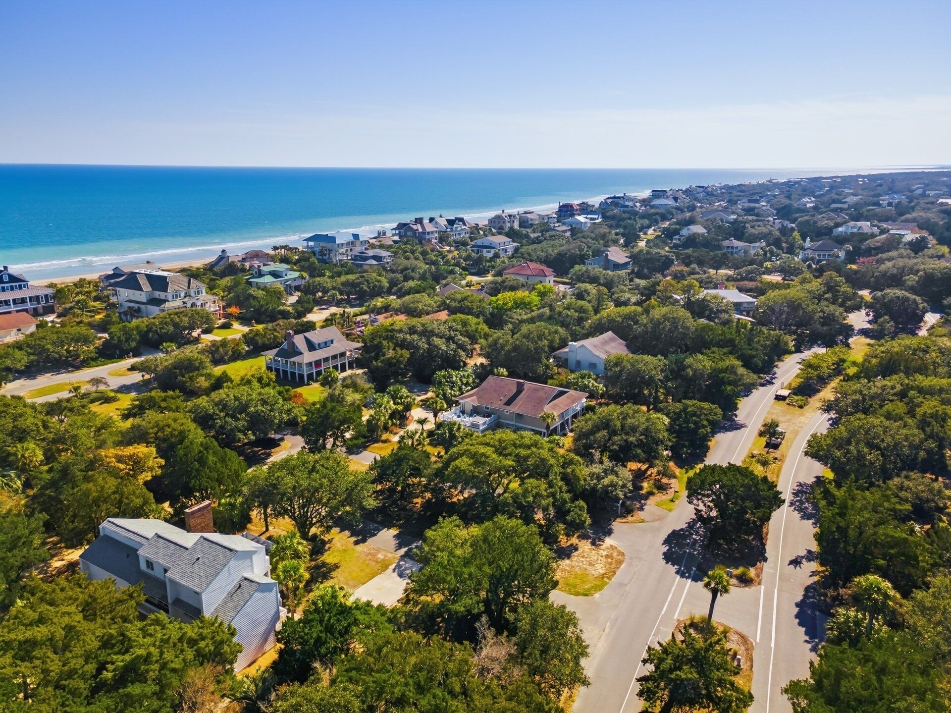 Vue aérienne d’une zone résidentielle côtière, avec des maisons, des routes et une plage.