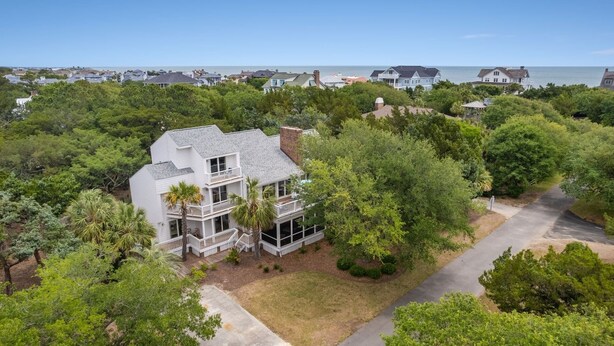 A two-story house with a balcony, surrounded by dense greenery and a view of the ocean. - Hellenic Haven 6 Bedroom Home (Georgetown)