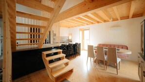 A spacious loft with exposed wooden beams, a kitchen area, and a dining space with modern furniture.