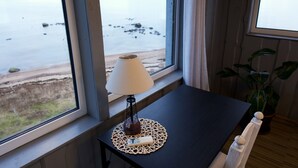 Une pièce avec une table près d’une fenêtre donnant sur une plage.