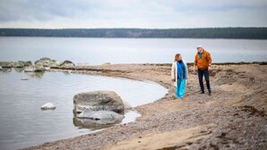 Deux personnes se tiennent sur une côte rocheuse, avec un lac en arrière-plan.