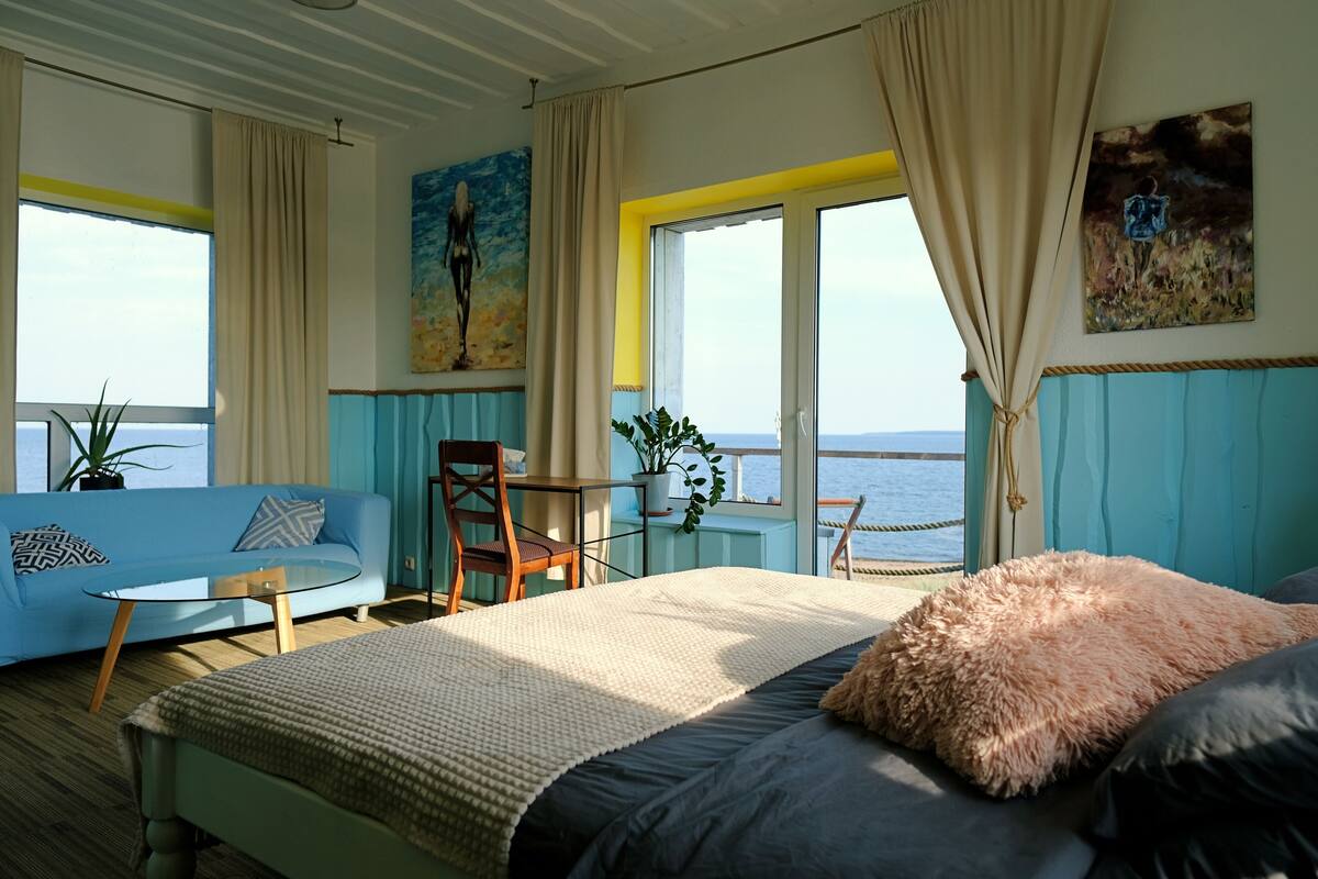 Ein Zimmer mit einem Bett, einem Schlafsofa, einem Sessel, einem Tisch und einer Topfpflanze.