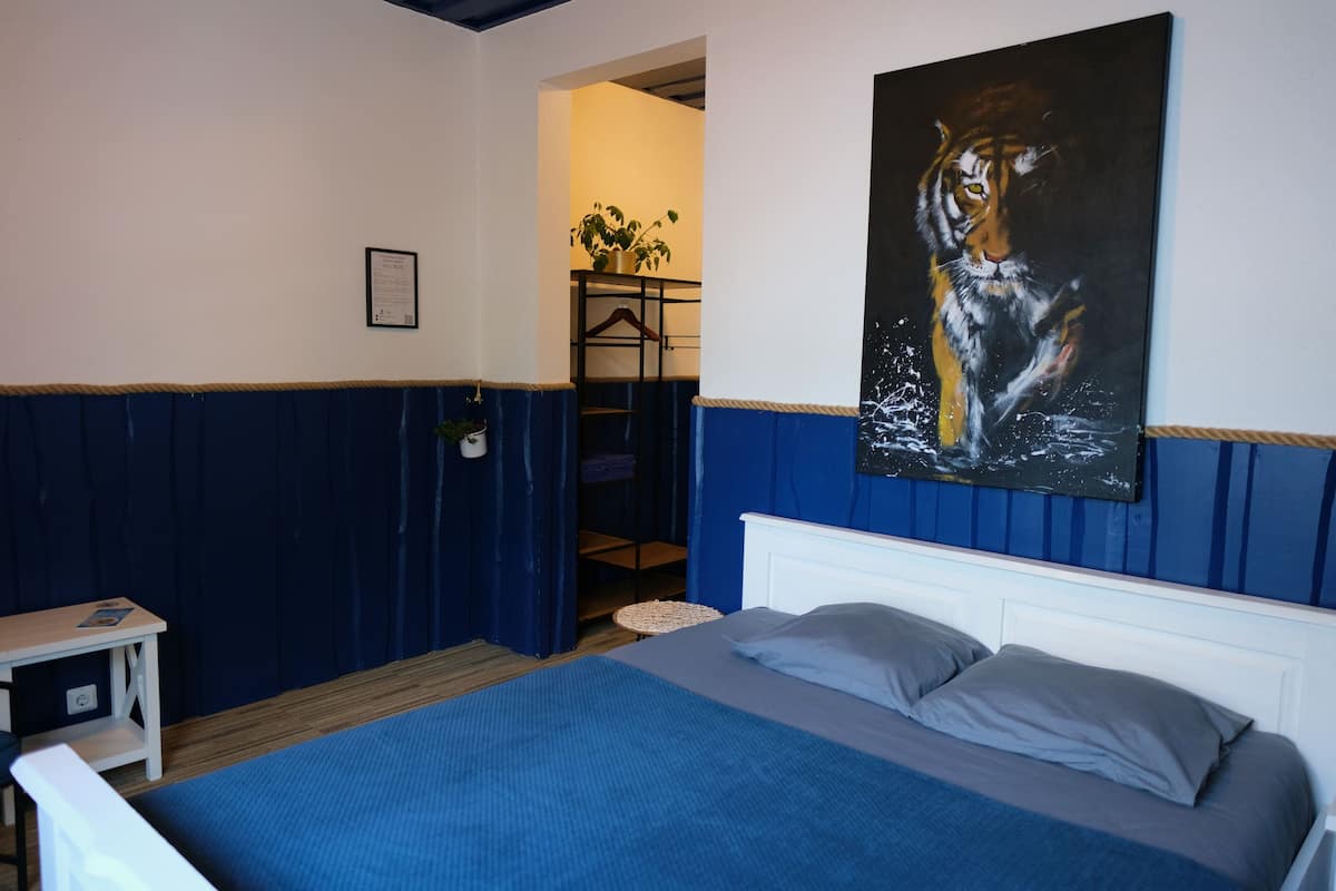 Ein Schlafzimmer mit einem Bett, einem Nachttisch, einem Gemälde und einer Pflanze.