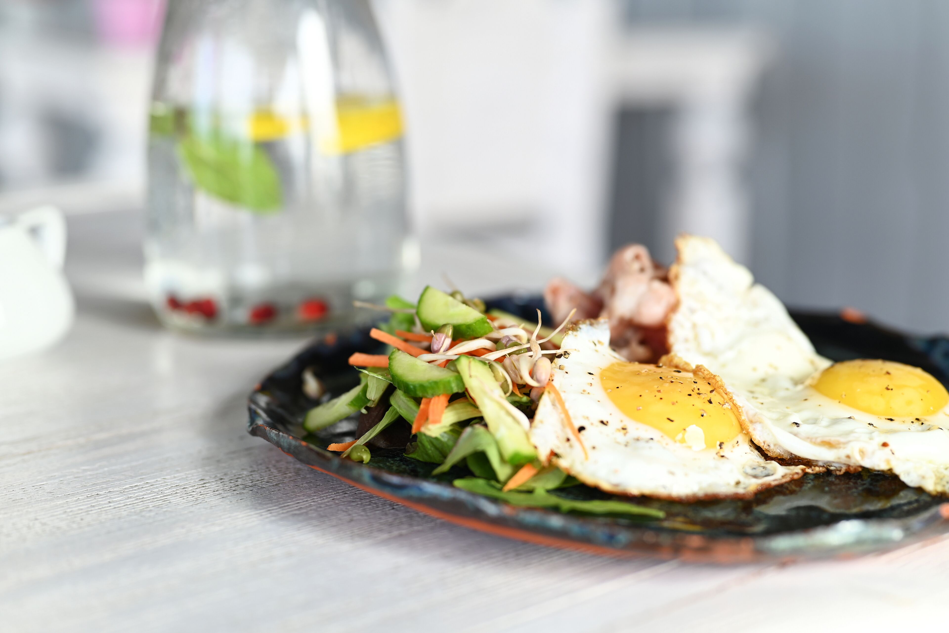 A plate with a salad and two fried eggs on a glass plate.