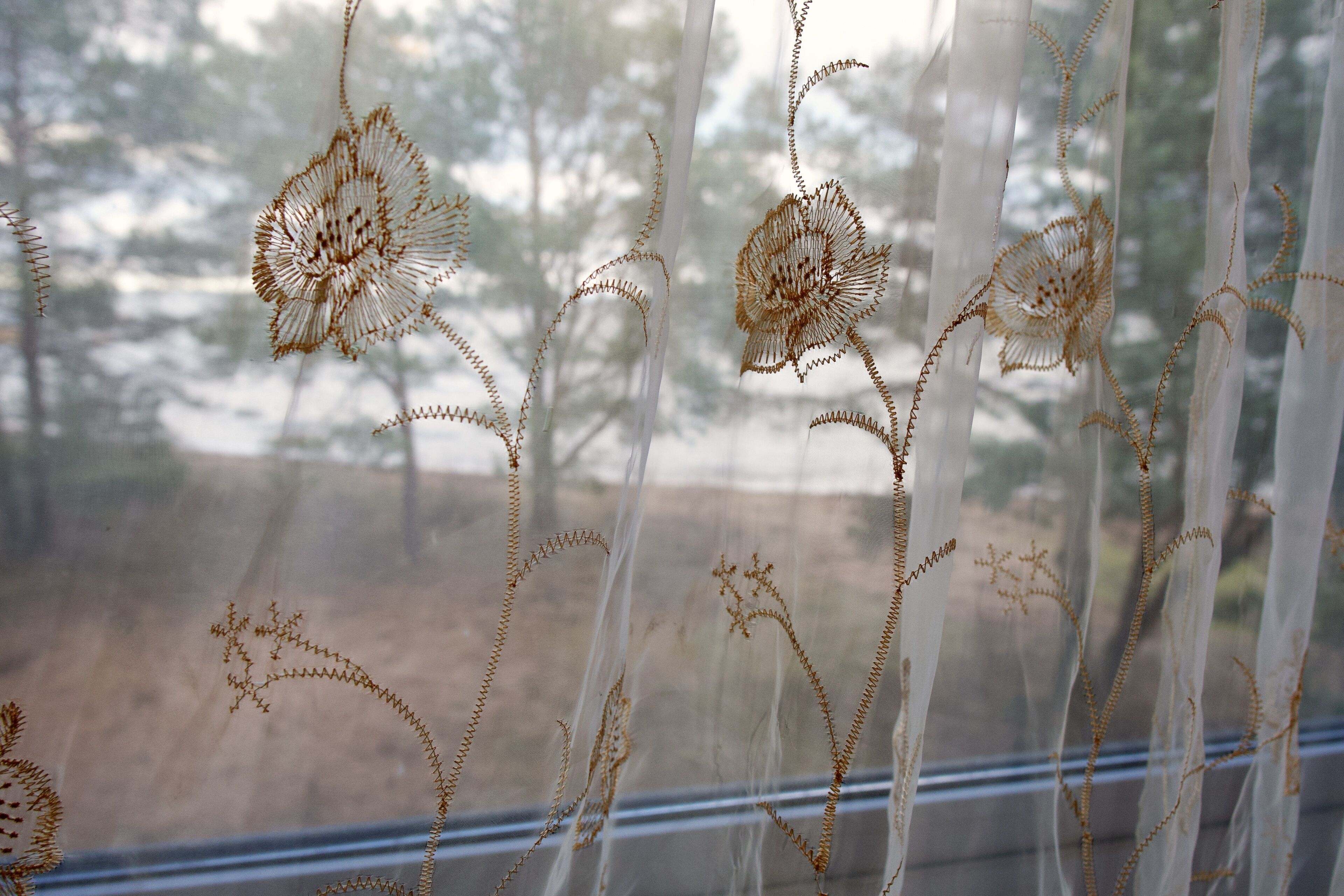 A window with decorative fabric featuring floral patterns.