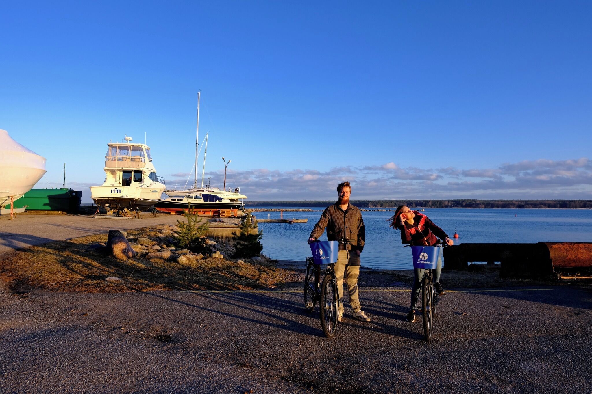A coastal area with a boat docked, a bicycle, and a person riding a bicycle.
