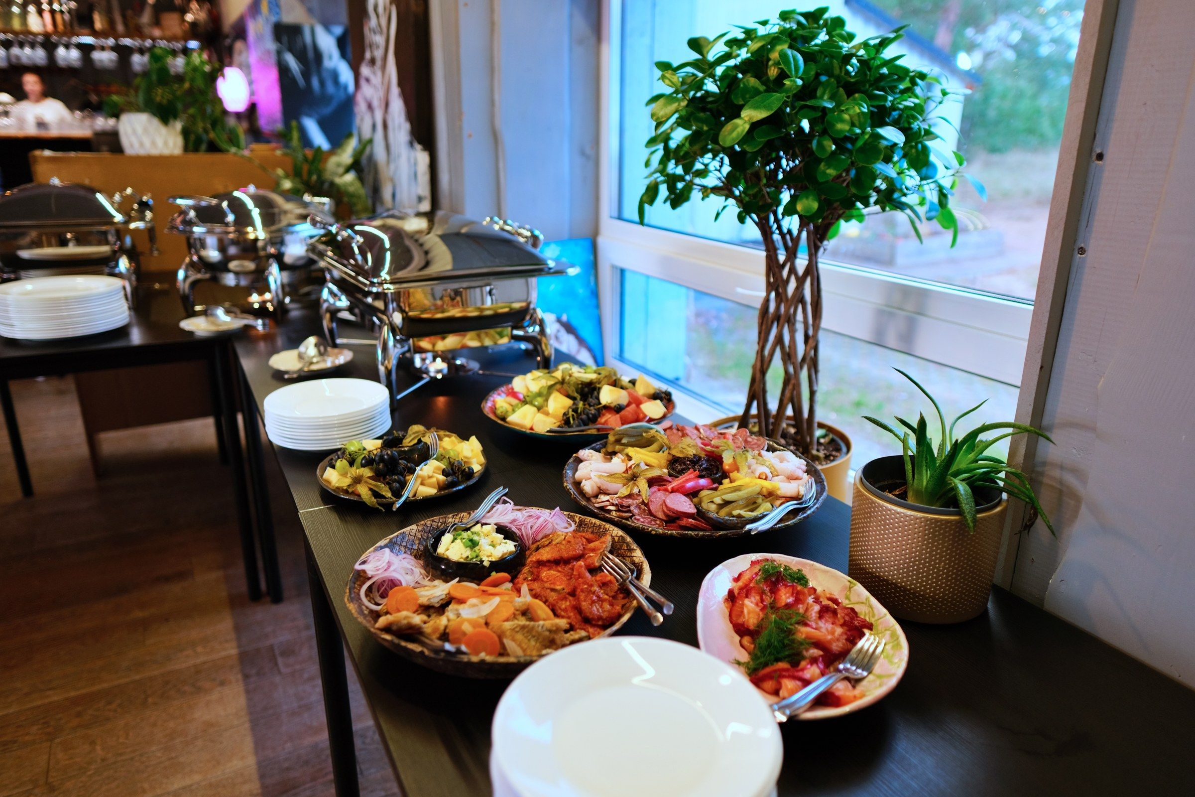 A buffet table with various dishes and a potted plant.