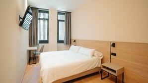 Une chambre d’hôtel moderne, dotée d’un grand lit, d’un bureau et d’une chaise.