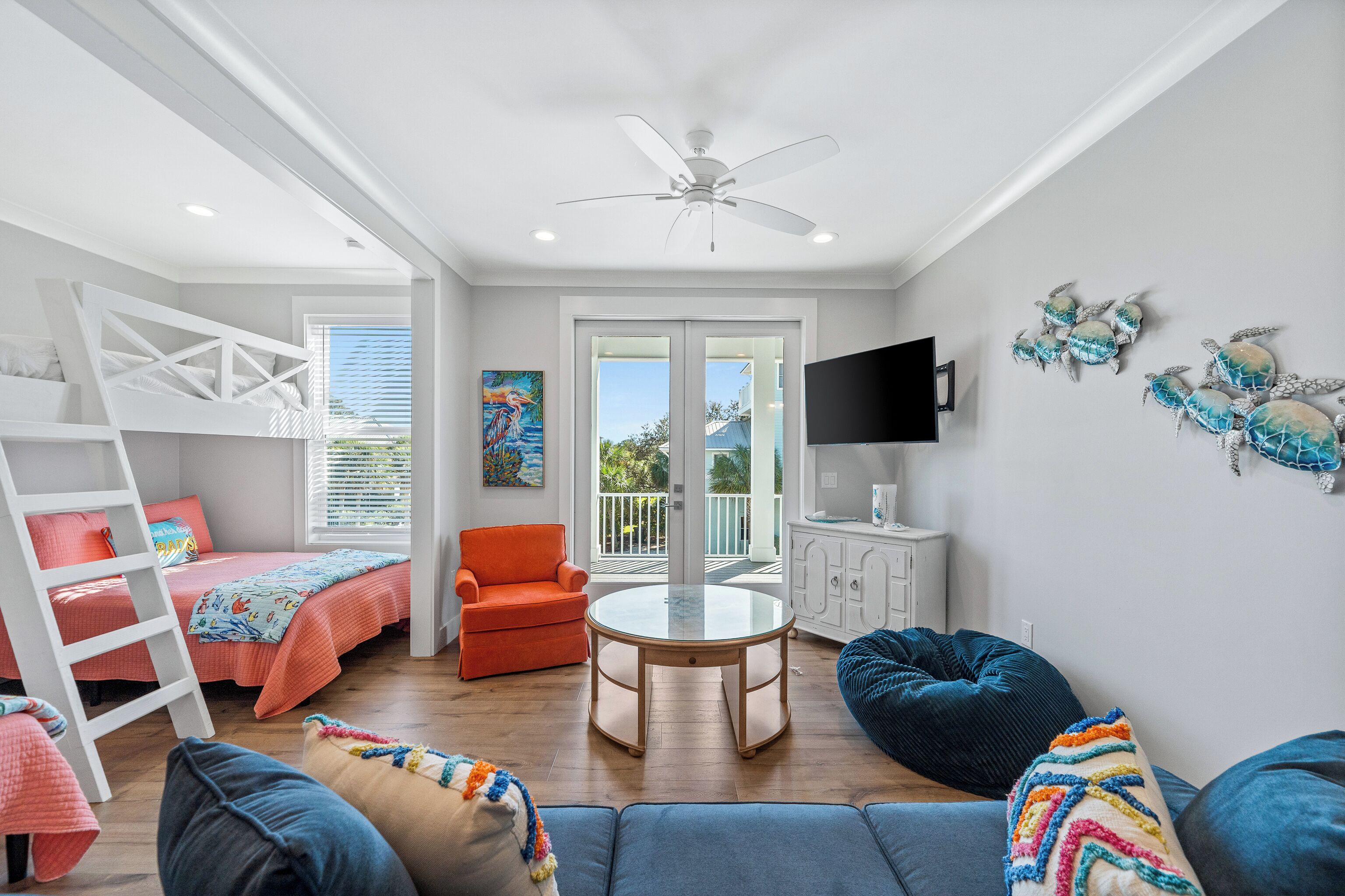 A bright, well-lit room with a bunk bed, a round table, a sofa, and a chair.