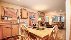 Una cocina acogedora con armarios de madera, una mesa de comedor con sillas y una chimenea.