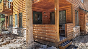 Una cabaña de troncos con cimientos de piedra, un porche de madera y un letrero que dice 'Welcome'.