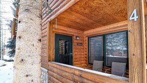 Una cabaña de troncos con un porche de madera, un cartel de bienvenida y un letrero con el número 4.