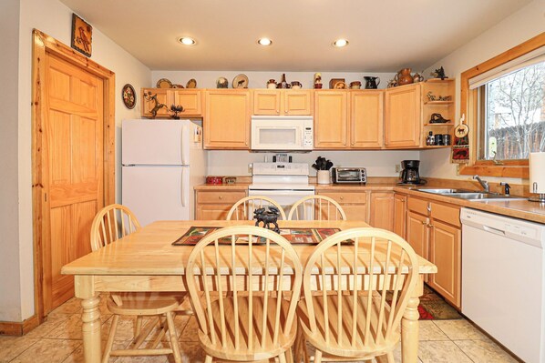 A kitchen with wooden cabinets, a white refrigerator, a microwave, a stove, a sink, and a window.