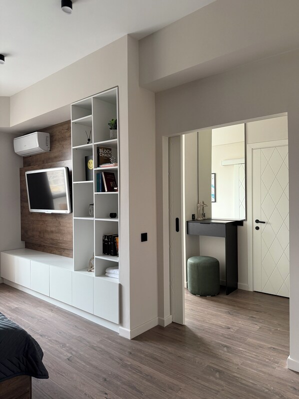 A modern living room with a built-in entertainment unit, a flat-screen TV, and a bookshelf.