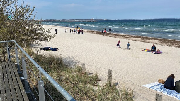 Una playa con un paseo de madera y una cerca de metal.