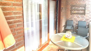 Una habitación con una mesa de vidrio, sillas, una pared de ladrillo y una puerta corredera de cristal.