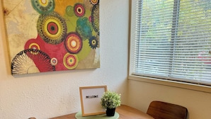 Uma mesa redonda de madeira com duas cadeiras, uma placa de boas-vindas e um pequeno vaso com planta.