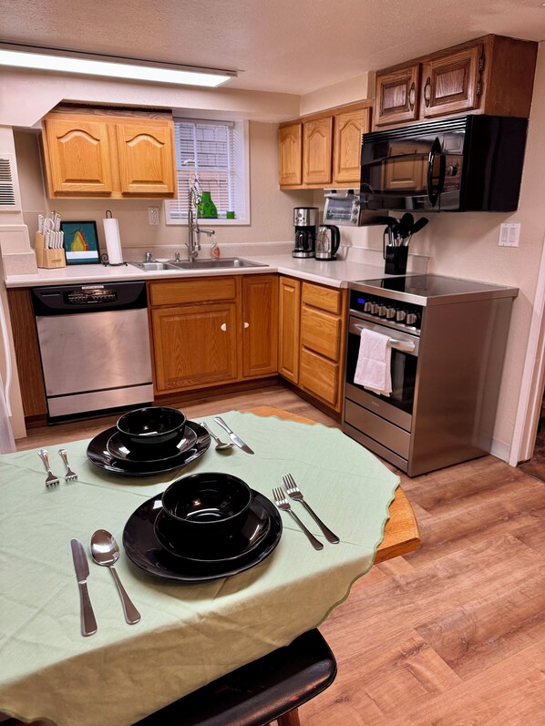 A kitchen with wooden cabinets, a stainless steel dishwasher, a stove, and a microwave.