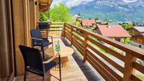 A wooden deck with a table and chairs, overlooking a mountain village with traditional houses. - Chalet Combloran Mont Blanc view (Combloux)