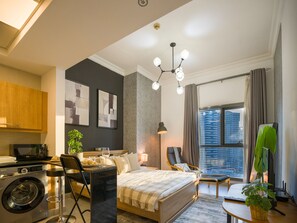 Relax in a spacious room with a large bed, seating area, and washing machine, offering a city view.