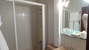 A bathroom with a glass-enclosed shower, a toilet, and a sink with a mirror above it.