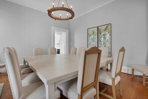 Un comedor con una gran mesa rectangular, seis sillas tapizadas y una lámpara de madera.