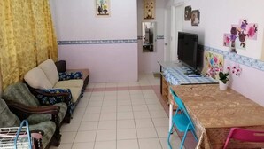 Una sala de estar con sofá, sillas, televisor y una mesa de comedor.
