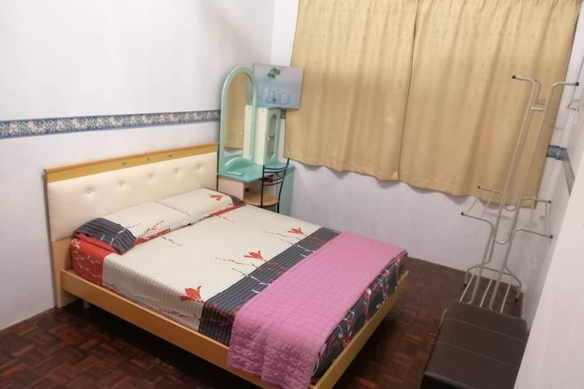 A bedroom with a bed, a nightstand, a mirror, and a window with curtains.