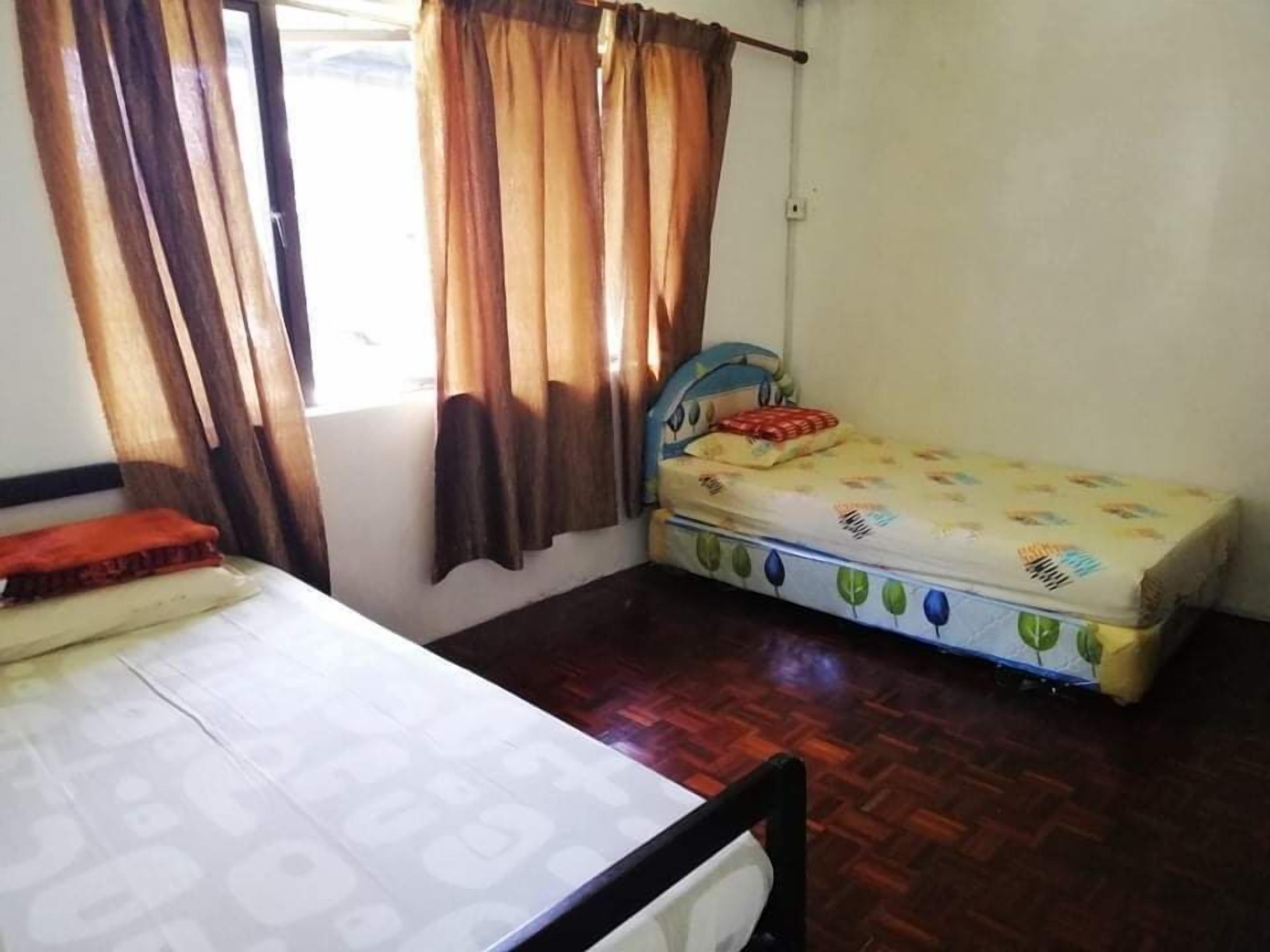 A small, single-room accommodation with a bed, a table, and a window with curtains.