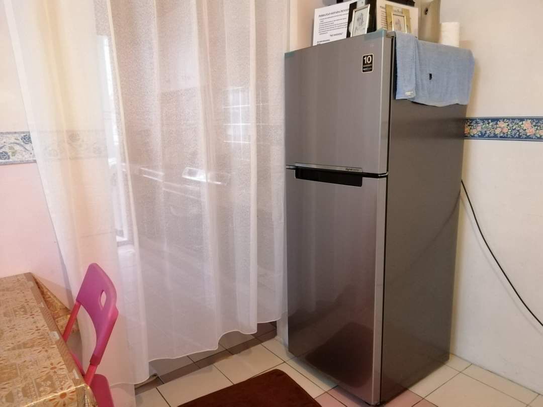 Een kleine keuken met een roestvrijstalen koelkast, een tafeltje en een stoel.