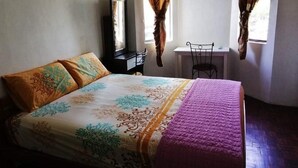Un dormitorio con cama, almohadas, un escritorio y una silla.