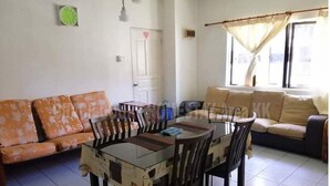 Una sala de estar con una mesa de comedor, dos sofás y una ventana con cortinas.