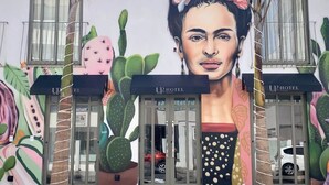 A hotel entrance with a mural of a woman and cacti, and the hotel's name displayed on the awnings. - UP Hotel Boutique (Bombinhas)
