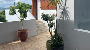 Een balkon met bloempotten, een rood dak en uitzicht op de lucht.