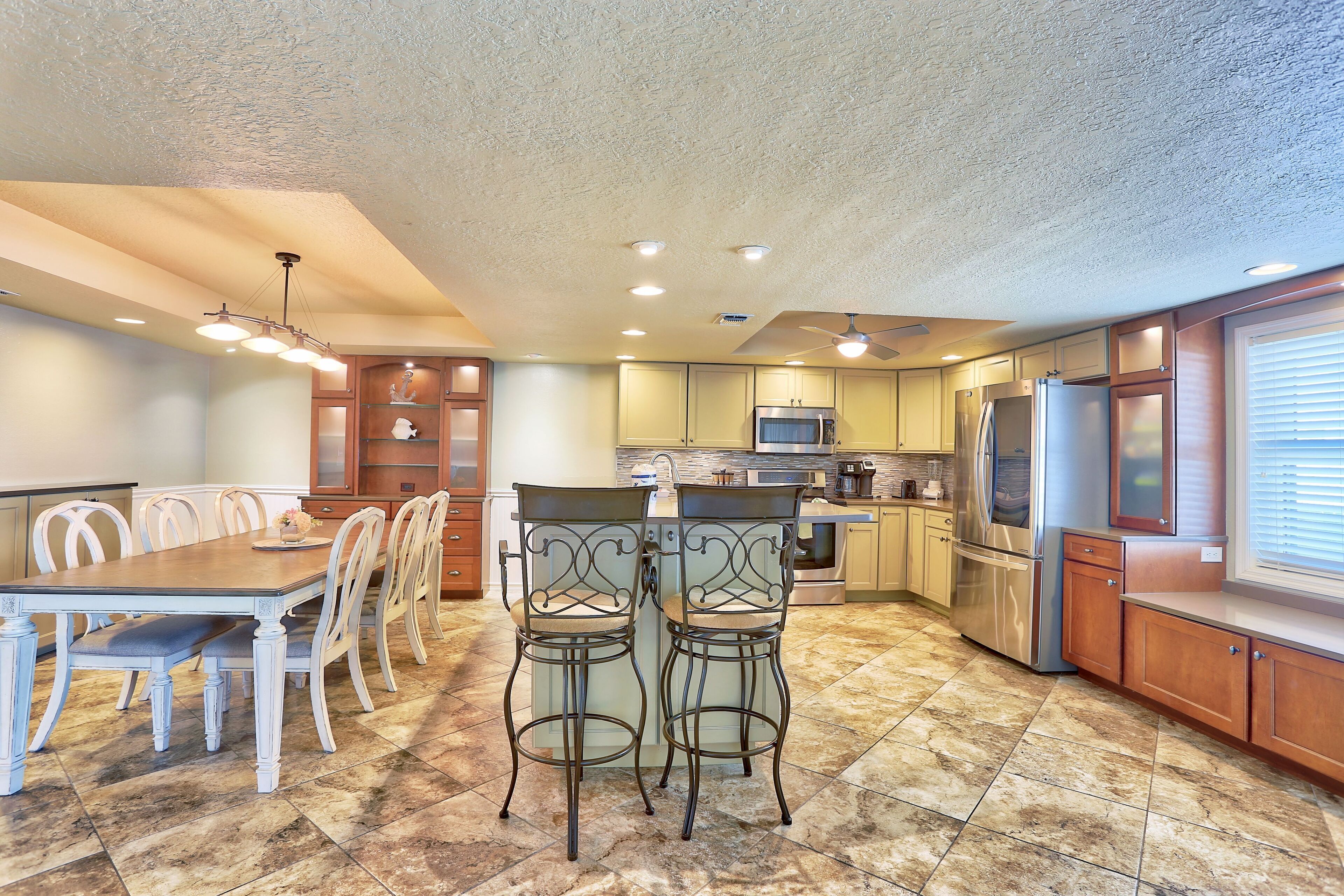 A spacious kitchen with a dining area, featuring a large island, modern appliances, and a ceiling fan.