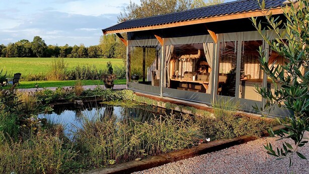 Un chalet rustique doté d’un porche abrité, d’un étang et d’un jardin.