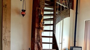 Un intérieur rustique avec un escalier en bois, une lanterne suspendue et un coin salon accueillant.