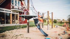 A playground with a slide, climbing net, and a wooden play structure. - Klaara-Manni Holiday Center (Randivälja)