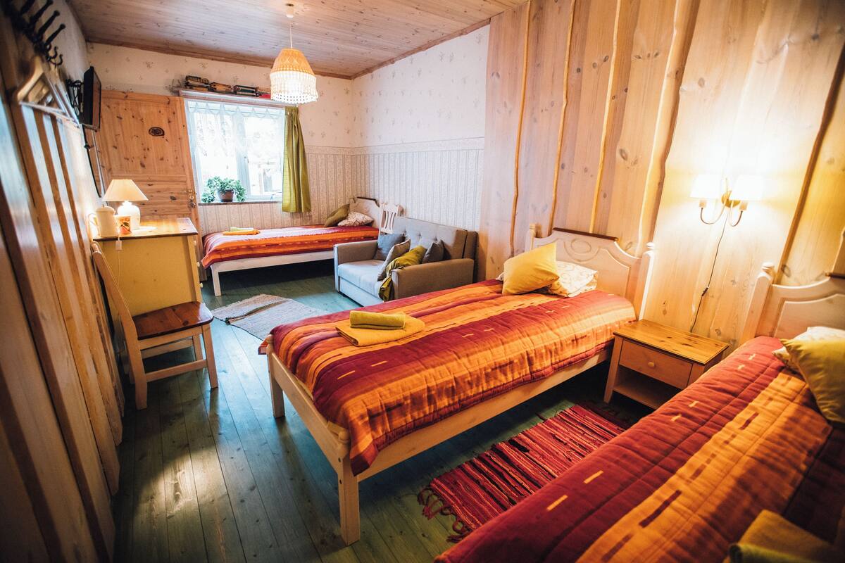 A cozy room with two beds, a wooden desk, and a window with curtains.