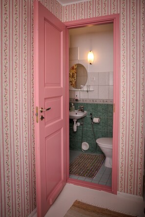 A bathroom with a pink door, a sink, a toilet, and a shower area. - Klaara-Manni Holiday Center (Randivälja)